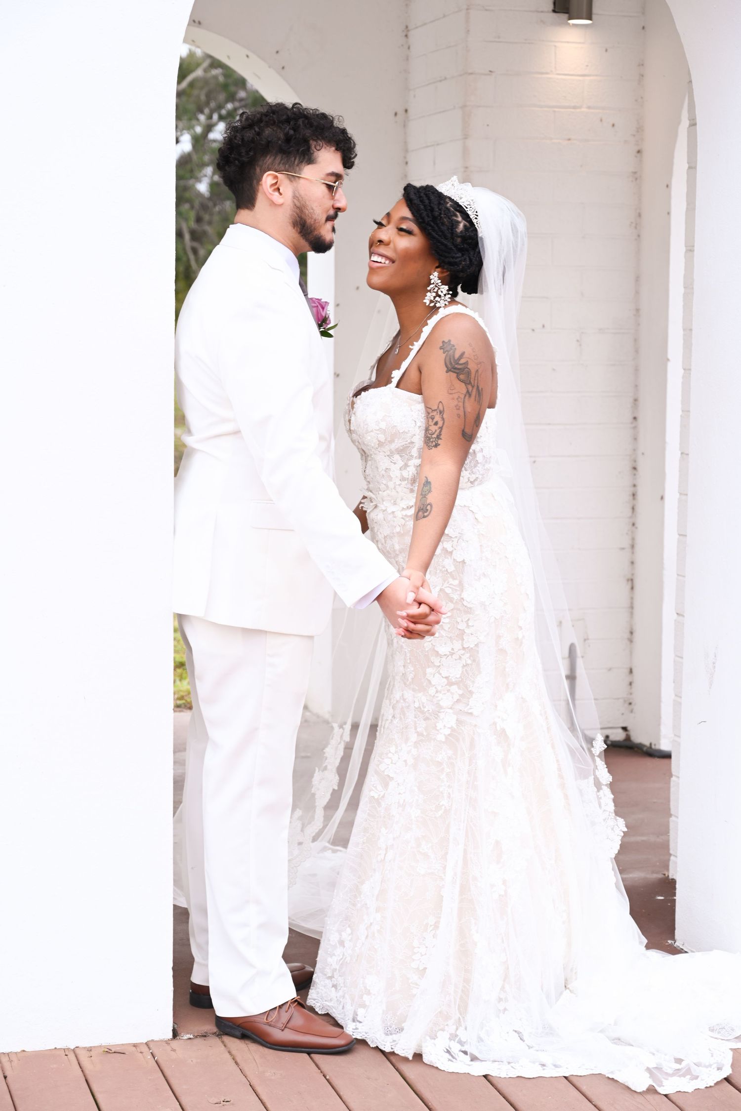 Romantic wedding photoshoot with couple in white attire against white columns.