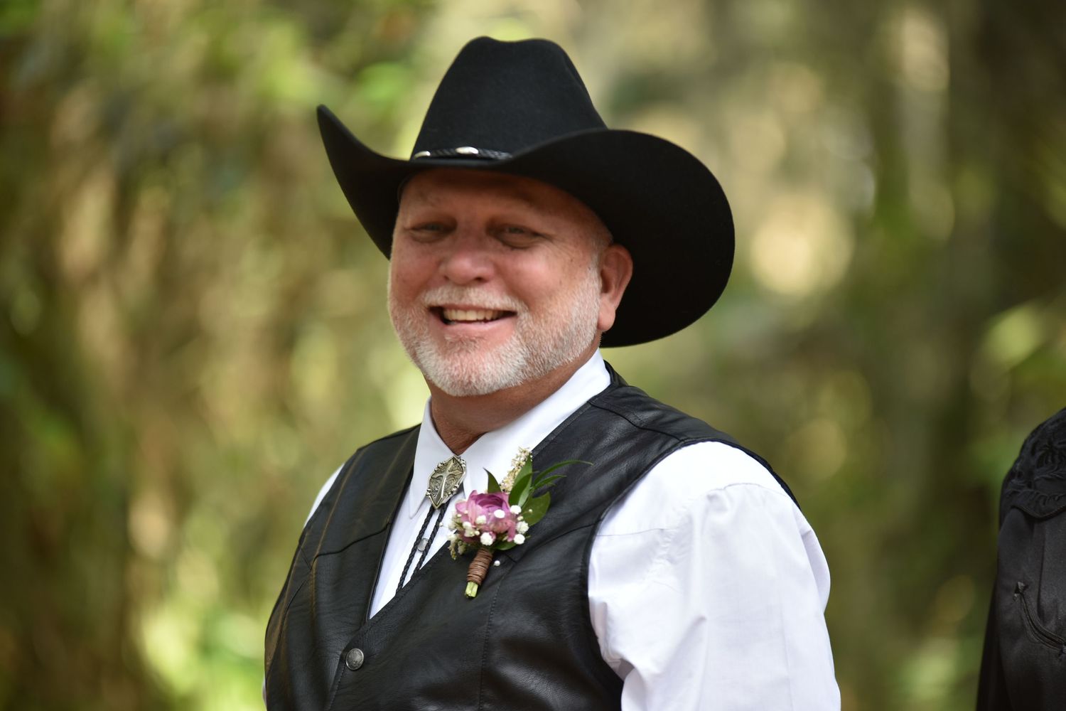 Wedding party members in black suits and cowboy hats smiling during an outdoor ceremony.