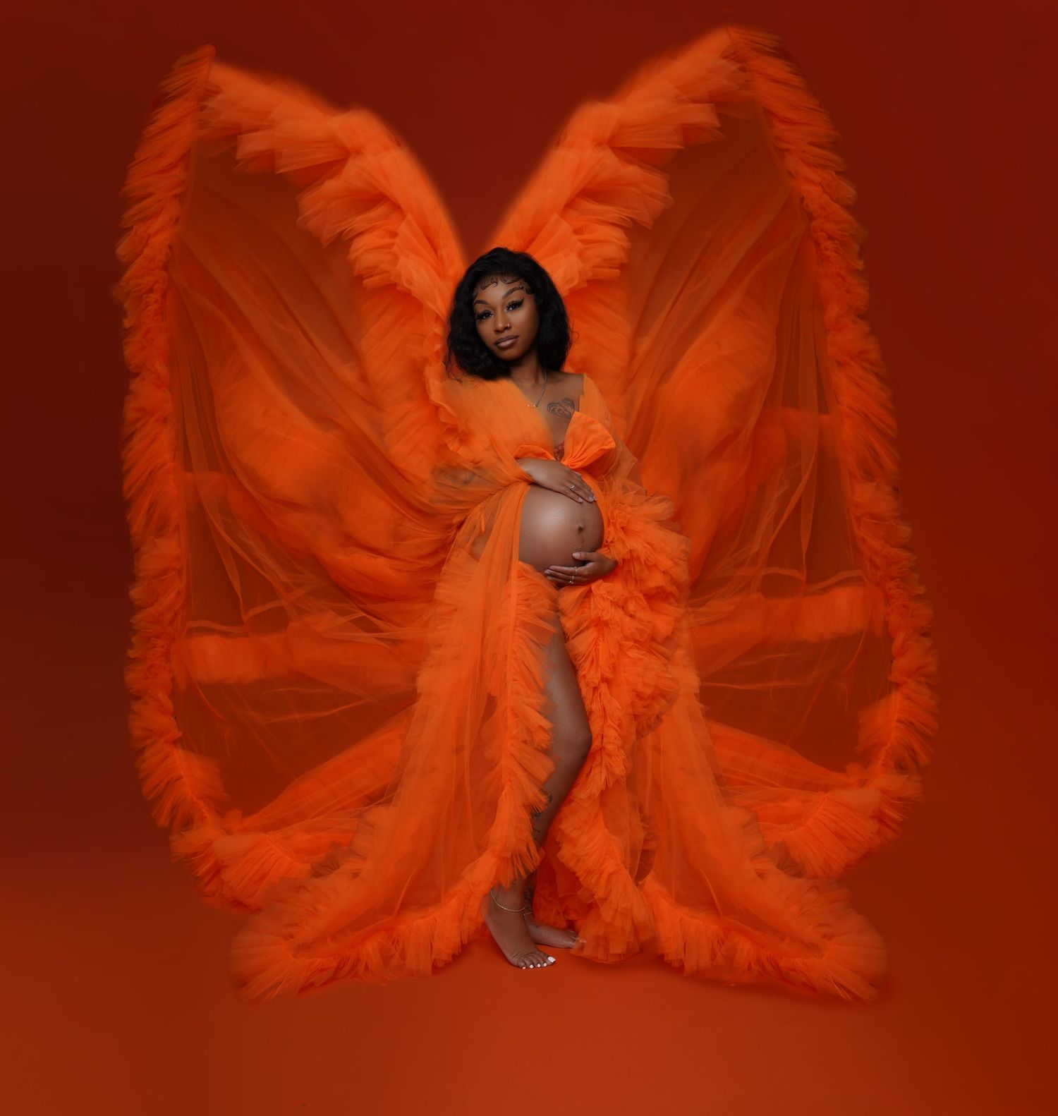 Orange wings made of fabric create ethereal butterfly effect in dramatic photoshoot.