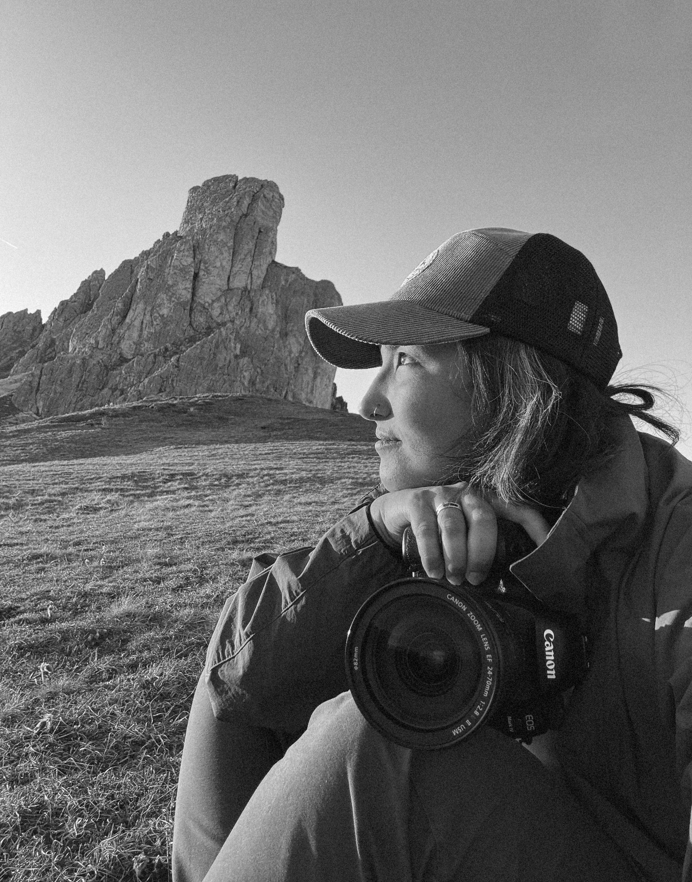 A series of black and white photographs showing someone using a camera in a mountainous landscape setting.