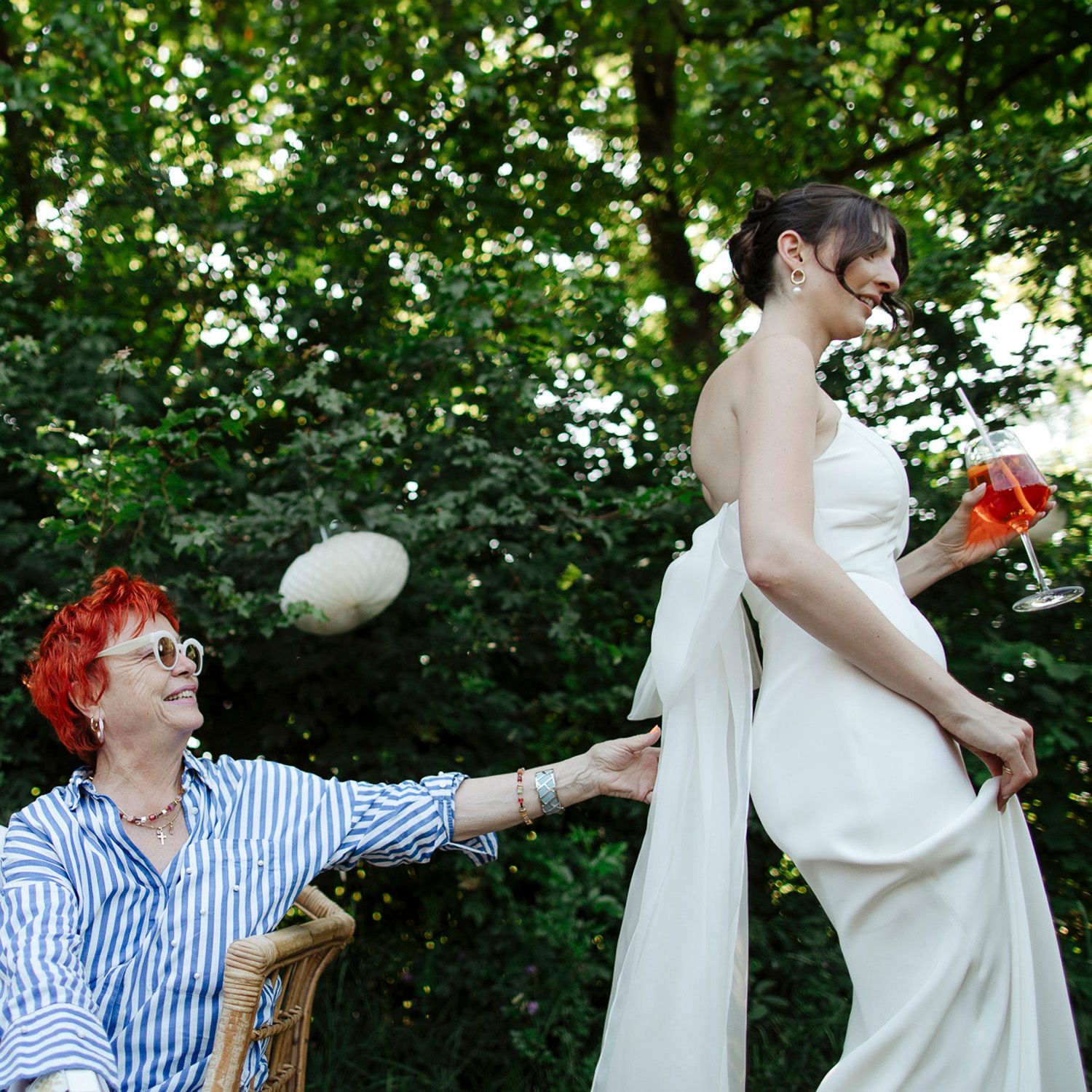 A whimsical outdoor scene with someone in a striped shirt tossing a balloon to a person in an elegant white outfit.
