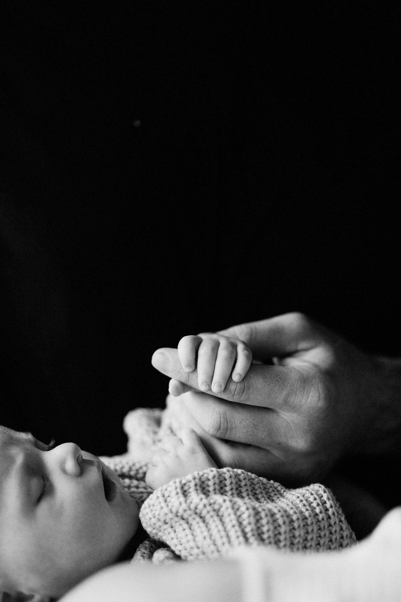 Black and white close-up photograph of hands tenderly touching in intimate moment.