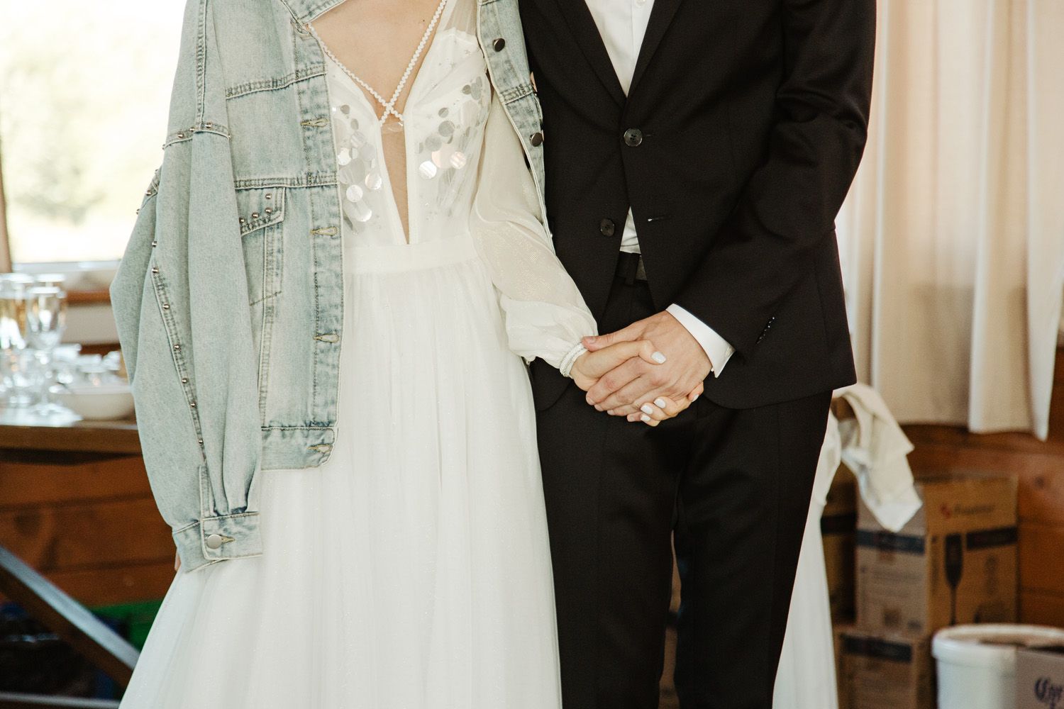 Elegant couple in formal wedding attire shown from shoulders down.