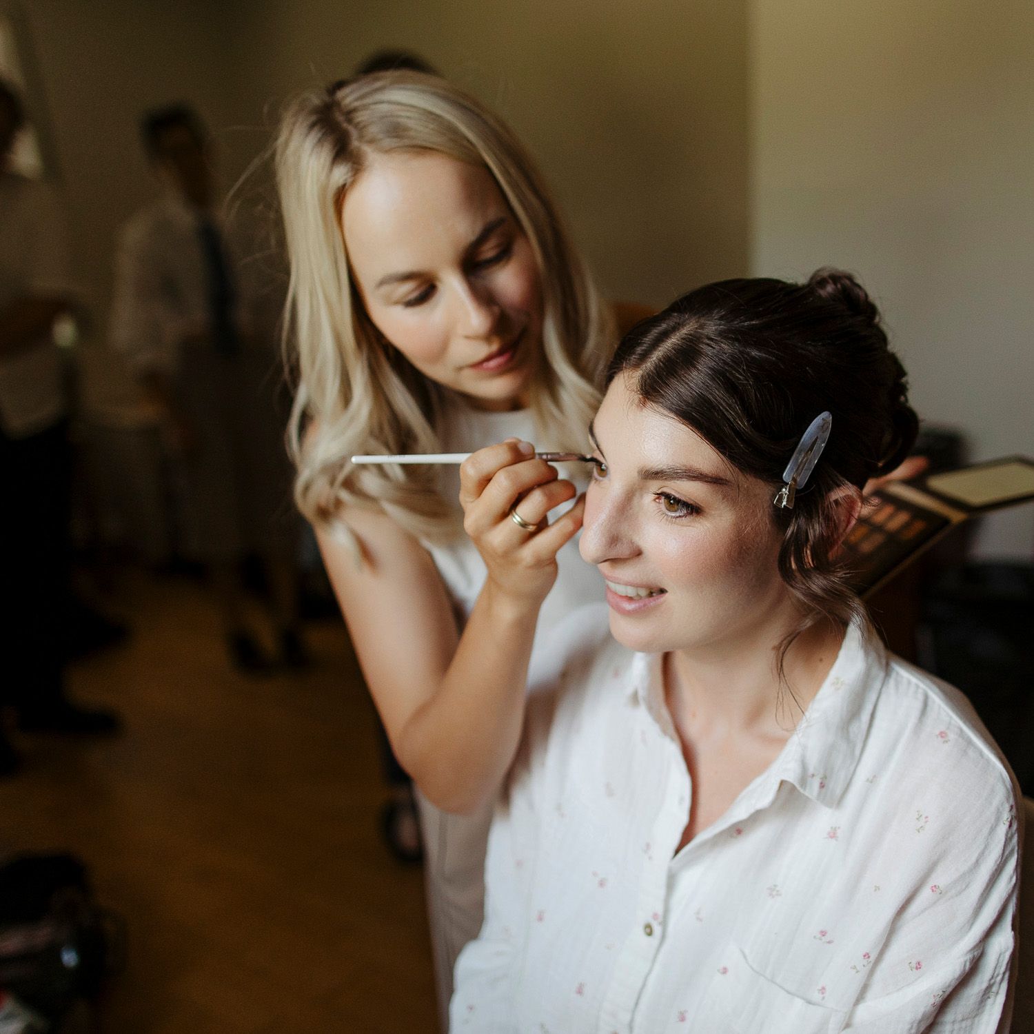 Makeup artist carefully applies cosmetics to client's face during professional beauty preparation session.