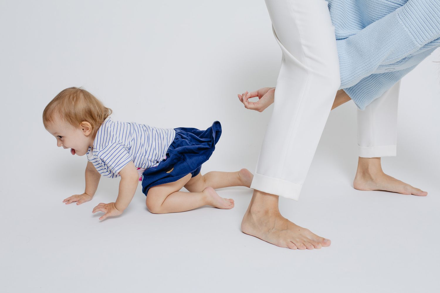 A sequence showing a toddler crawling and playing on a white floor in blue pants.