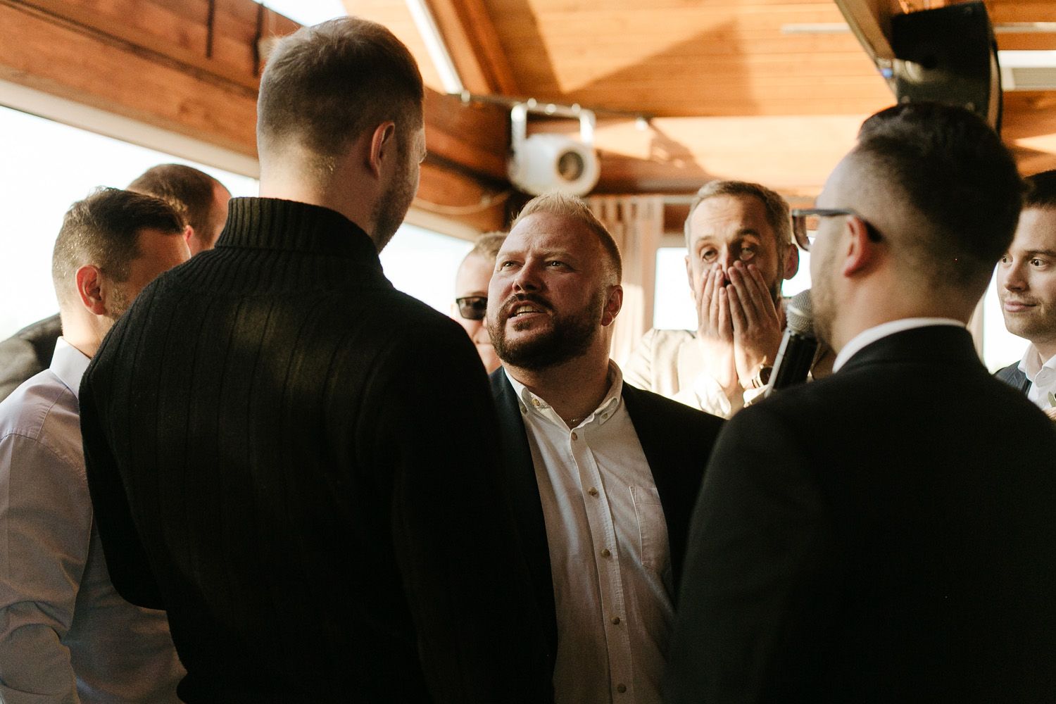 Wedding guests gathered in wooden interior venue with warm lighting.