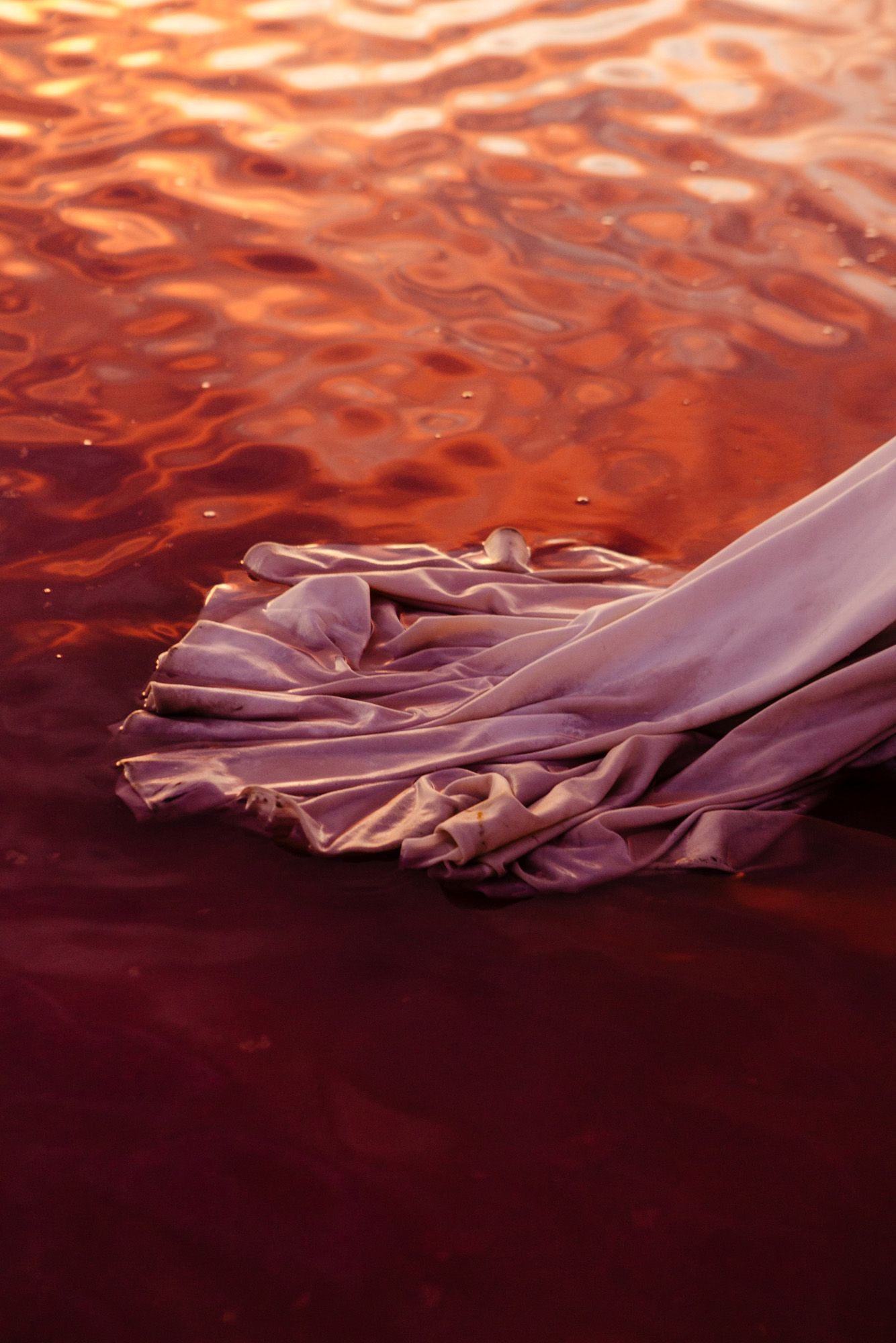 Abstract rippling water surface in vibrant orange and purple hues creating flowing patterns.