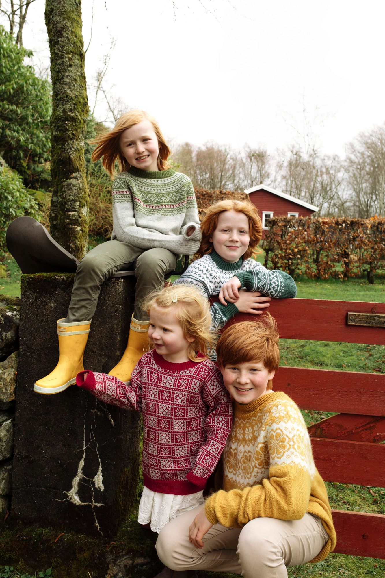 A cheerful group in colorful winter sweaters poses by a red barn in the background.