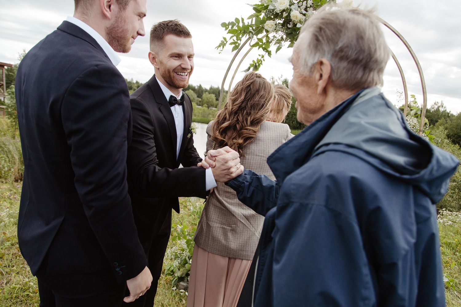 Wedding celebration with guests gathered outdoors near a decorative arch.