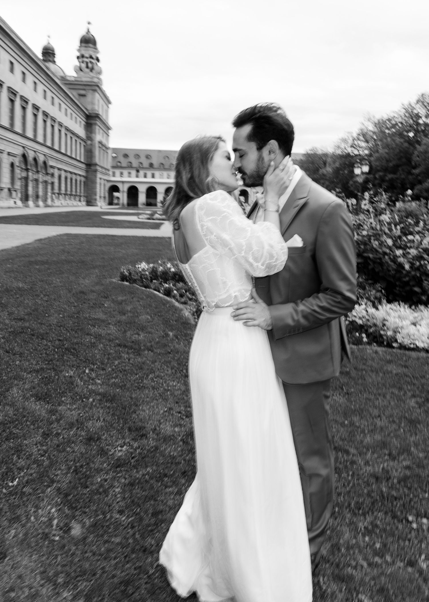 Romantic black and white photo series showing a couple in wedding attire embracing on a grassy hillside near a church.