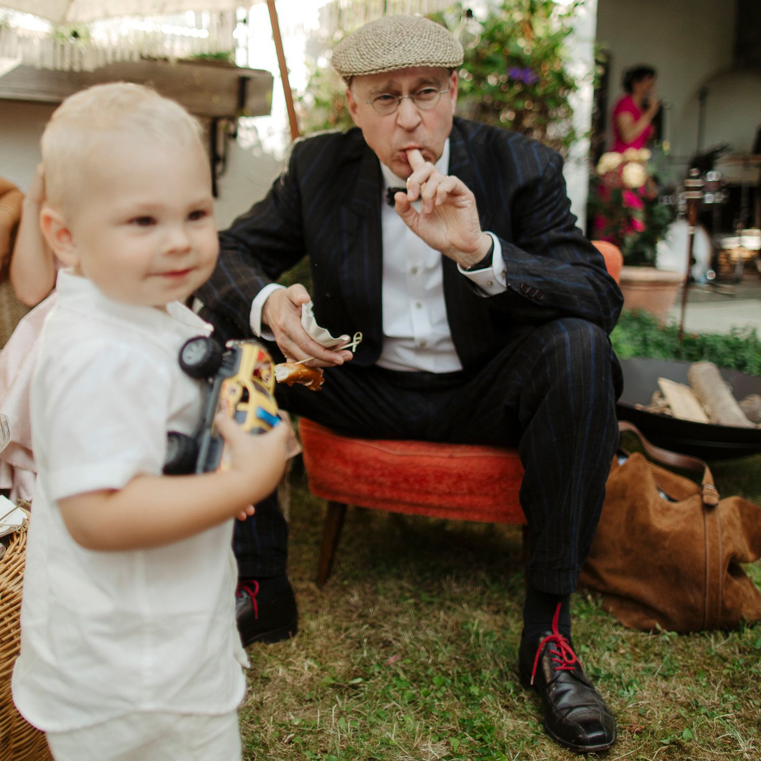 Small children in formal attire playing on grass during an outdoor event.