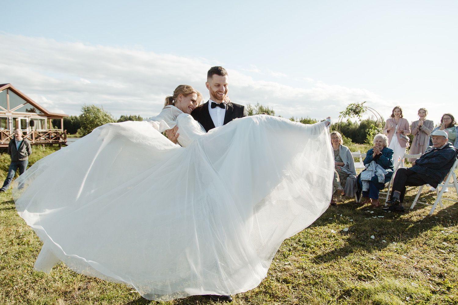 Flowing white wedding dress billowing in the wind during outdoor celebration.