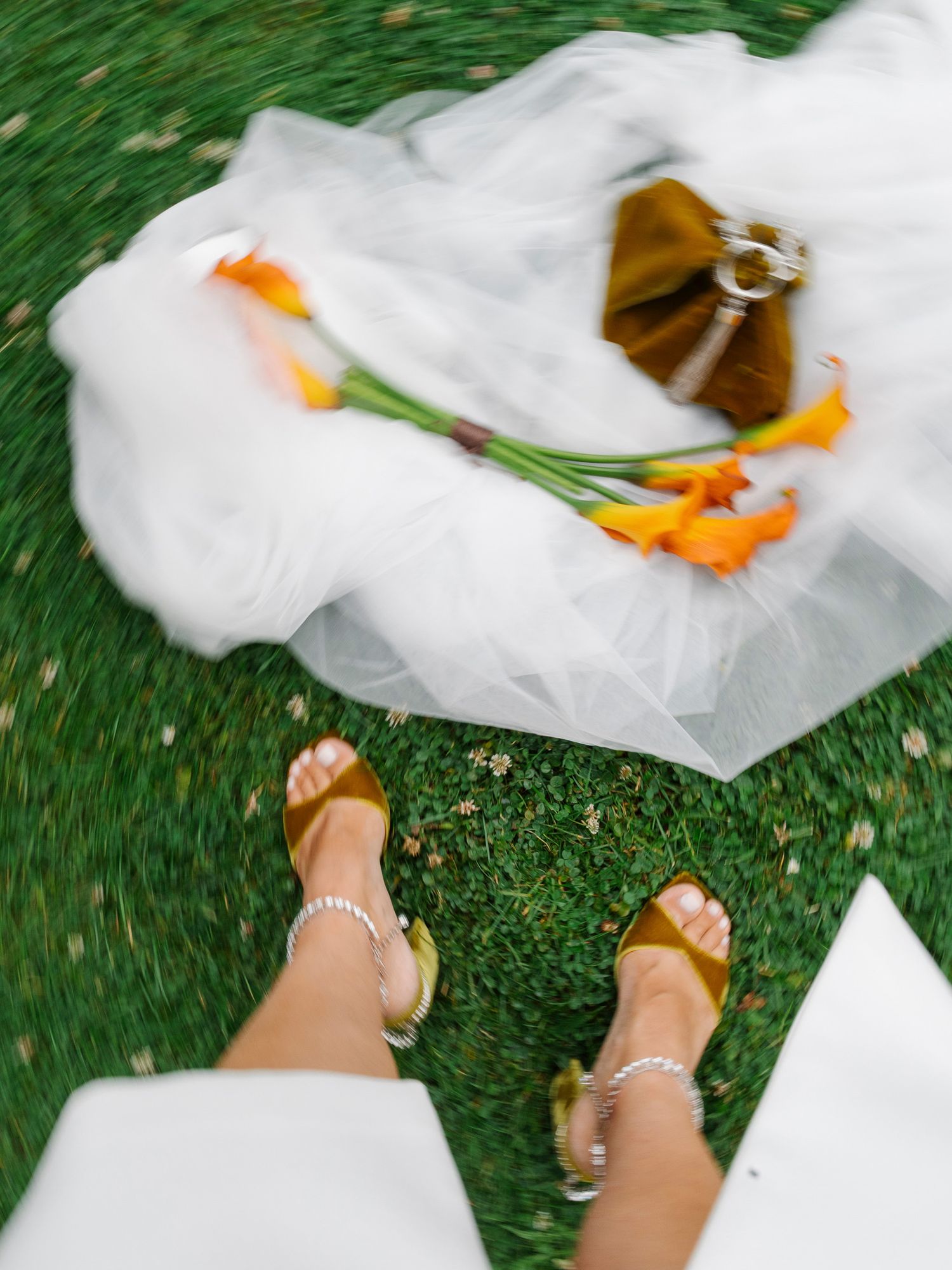 White fabric flutters in the breeze against green grass with sandaled feet visible in the corner.