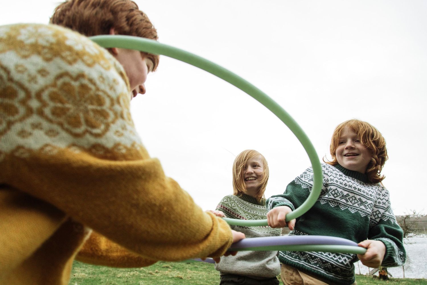 Individuals manipulating colorful hoops in a coordinated outdoor activity.