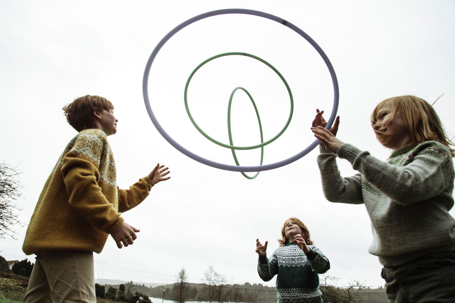 People tossing circular hoops in a playful outdoor scene.