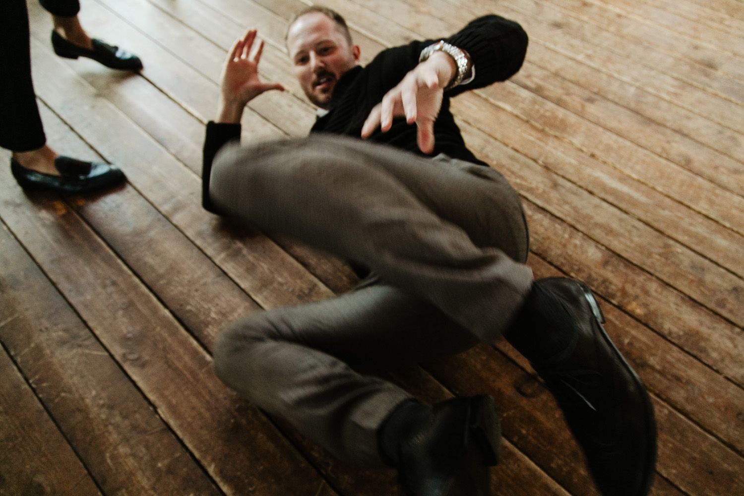 People dancing and celebrating on rustic wooden floor at wedding reception.