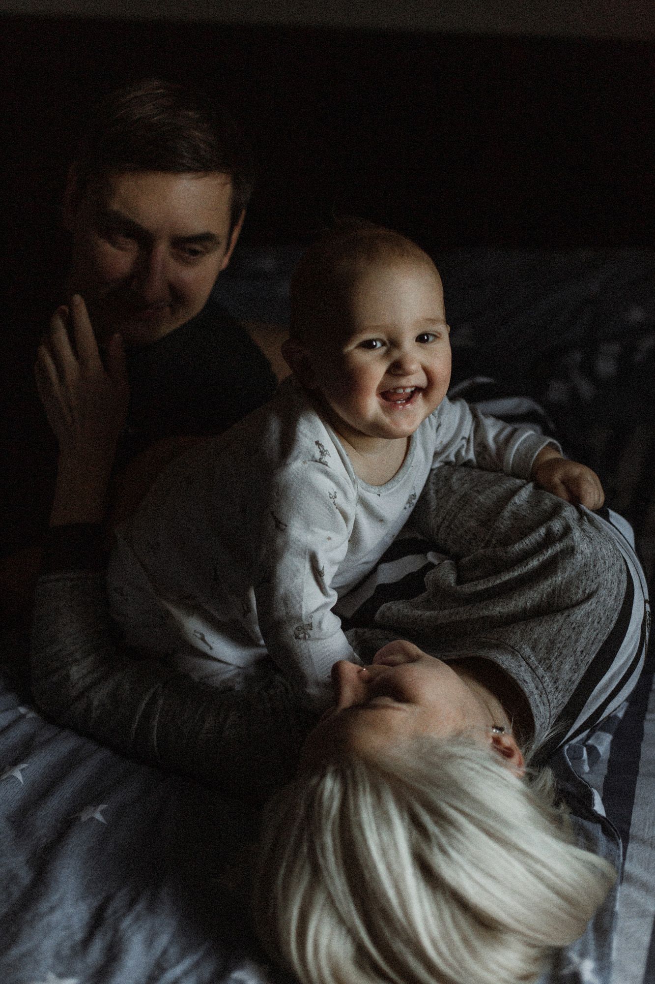 Intimate low-light portraits showing tender moments of affection and laughter in a dark setting.