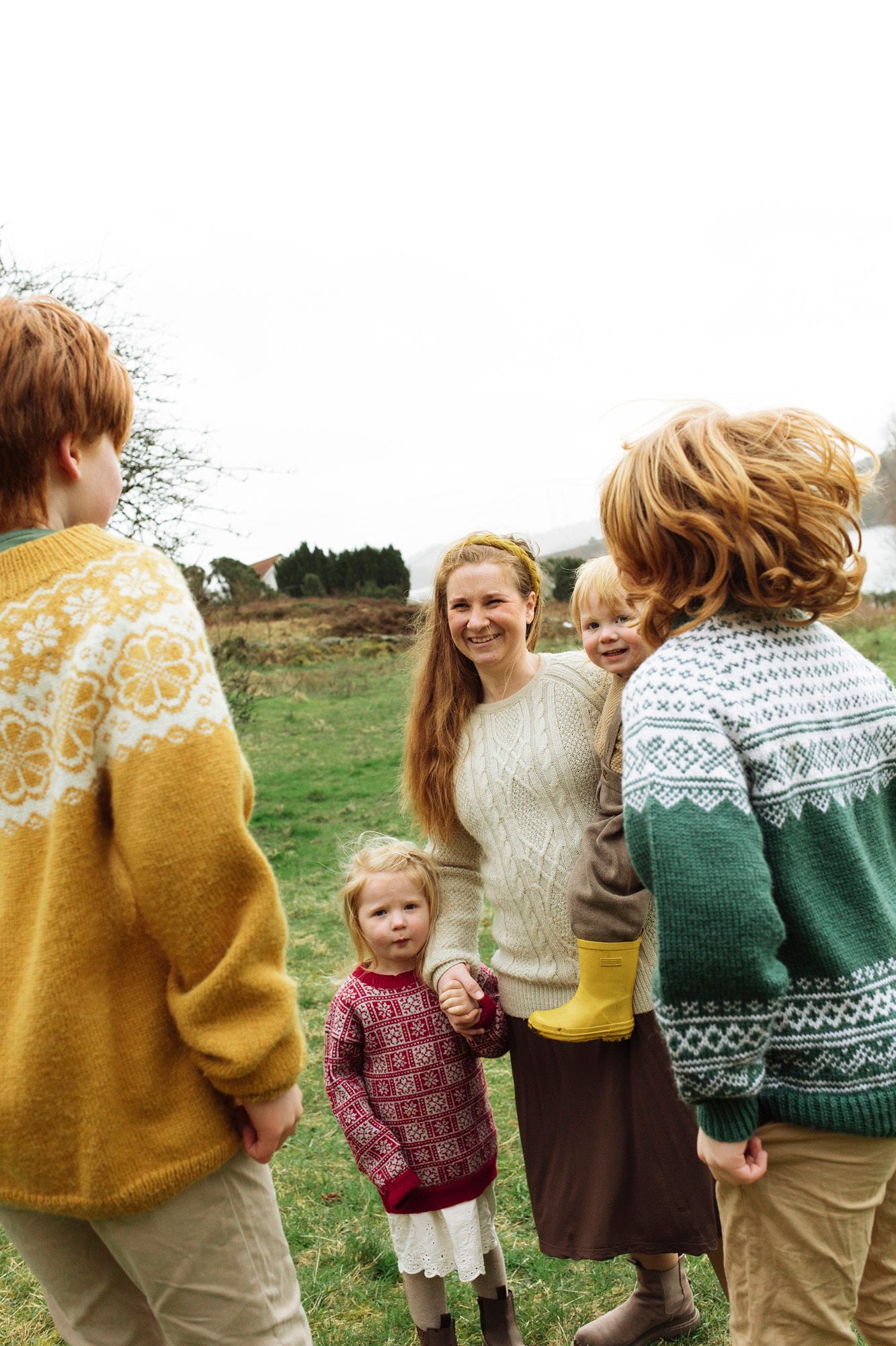 Group wearing coordinated knit sweaters posing together in a casual outdoor setting.