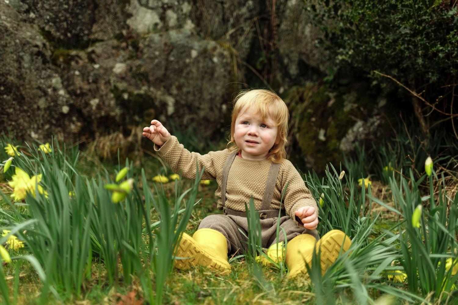 Young family enjoying springtime in a garden with yellow daffodils blooming.