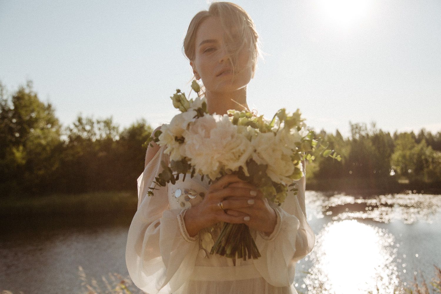 Sunlit outdoor wedding scene with waterfront backdrop during golden hour.