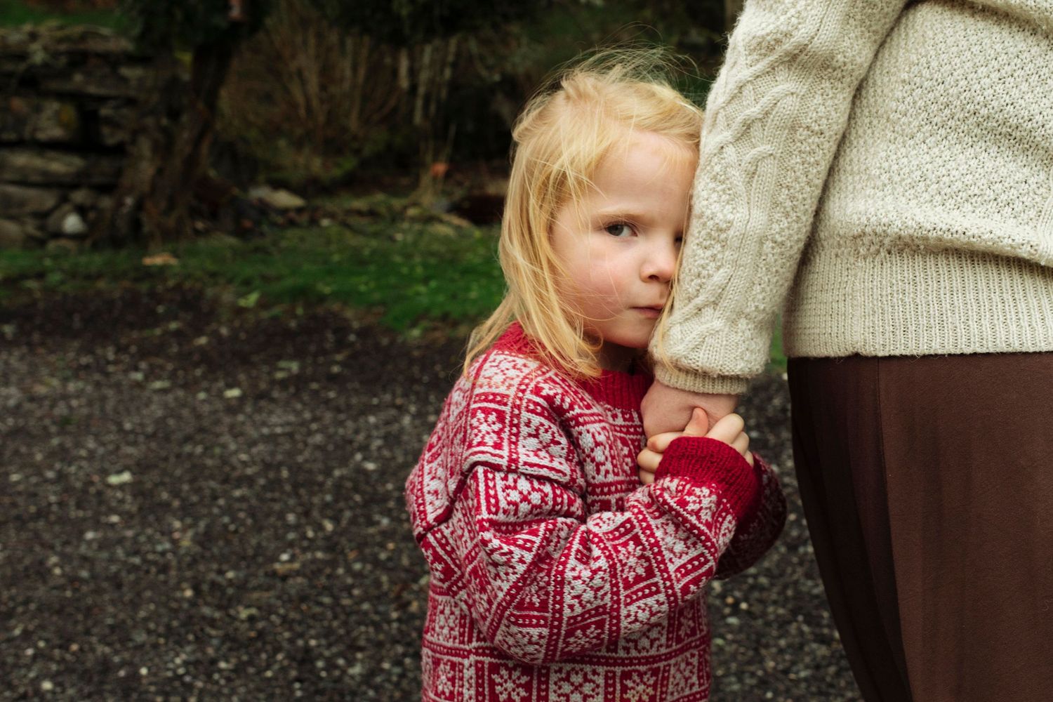 Sweet tender moment between parent and child in cozy knit sweaters outdoors.