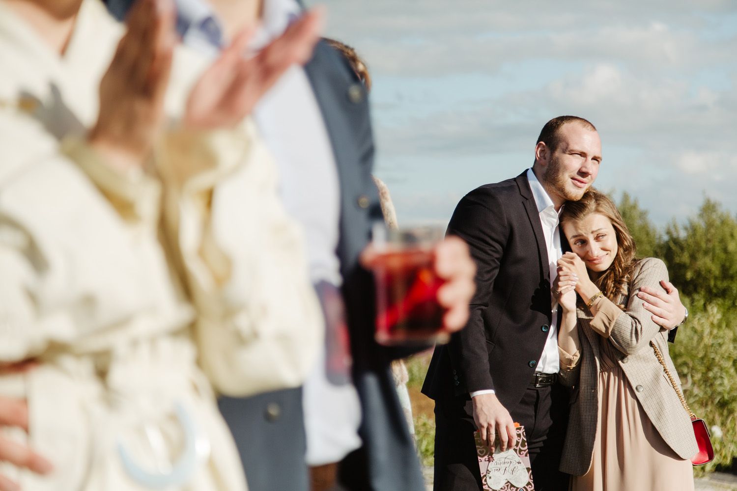 Wedding party members dancing and celebrating during outdoor daytime reception.