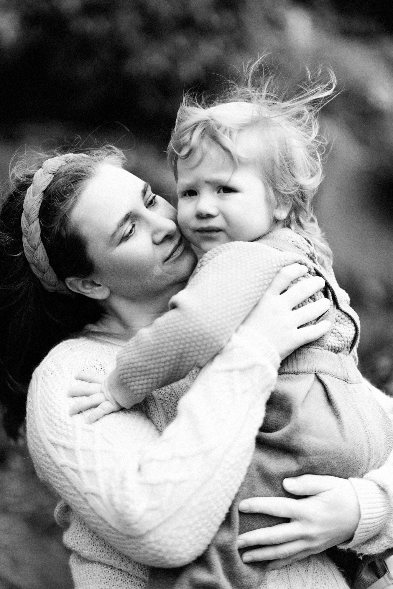 An intimate black and white portrait showing a loving embrace in matching knit sweaters.