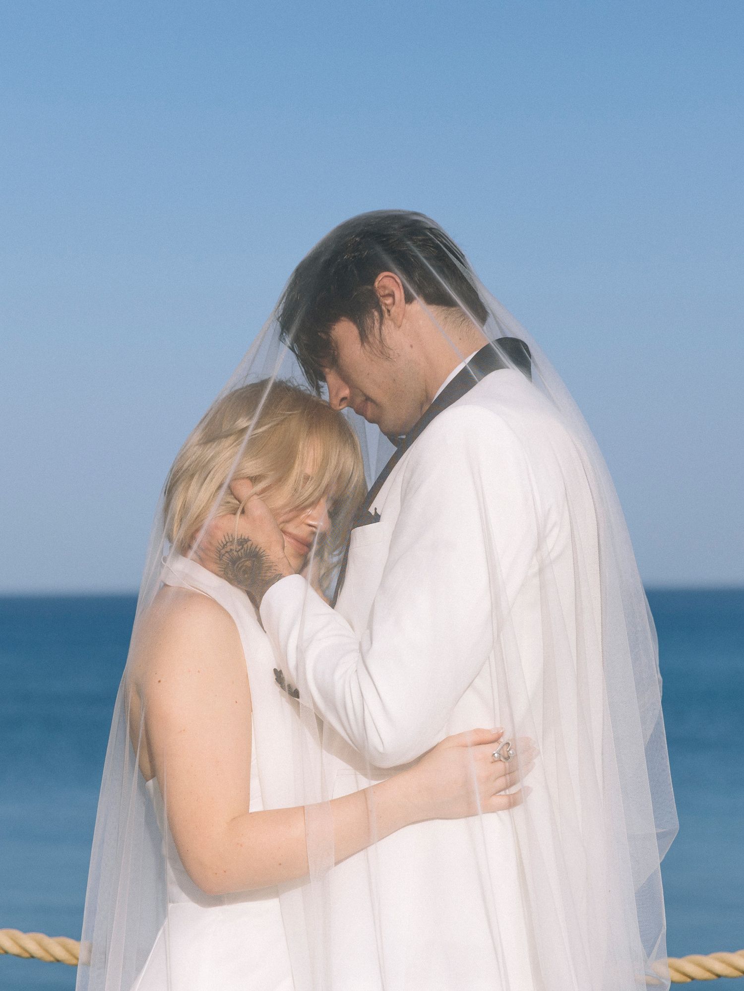 A romantic beach wedding sequence shows a couple embracing by the ocean under a flowing white veil.