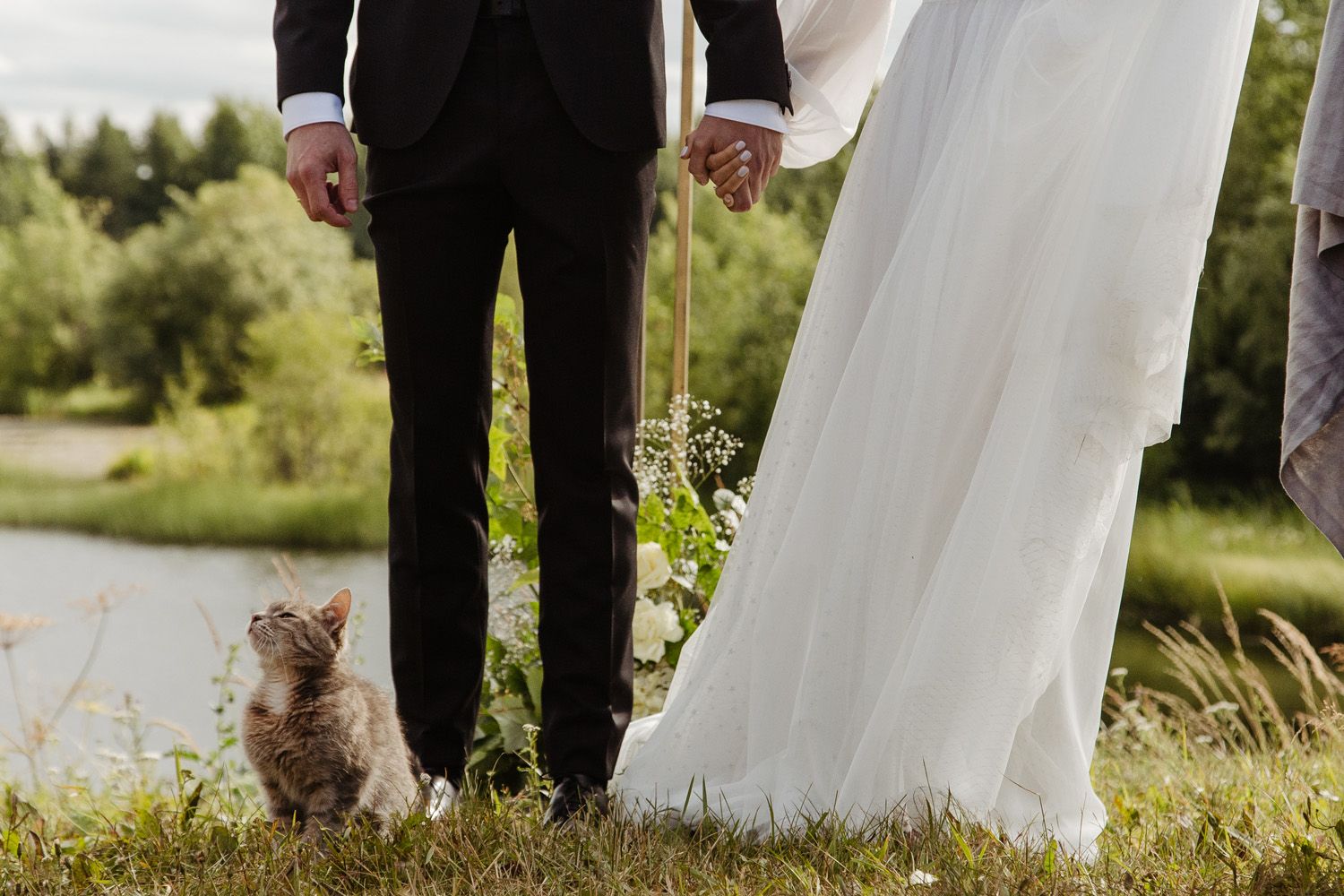 Outdoor wedding ceremony with flowing white dress details against natural scenery.