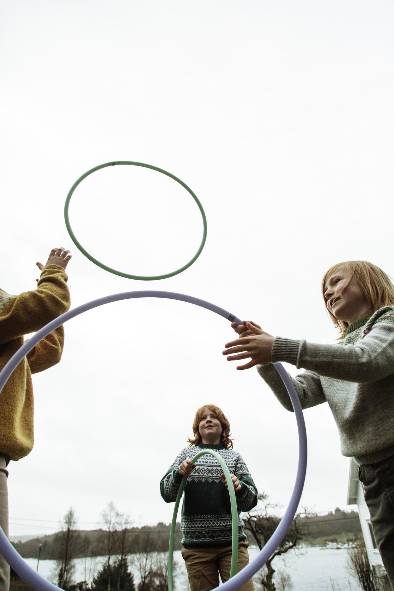 Group engaged in playful activity with a hoop against a winter sky.