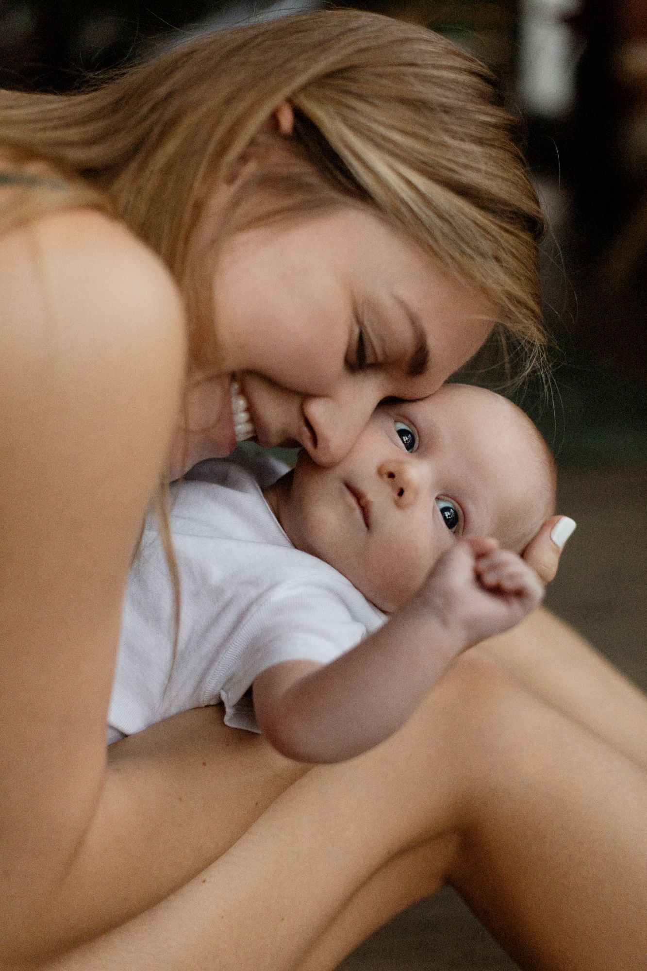 Tender moment captured between parent and infant in soft natural lighting.