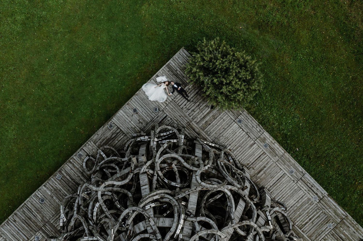 A series of aerial photos showing a stone labyrinth design carved into green grass in a garden setting.