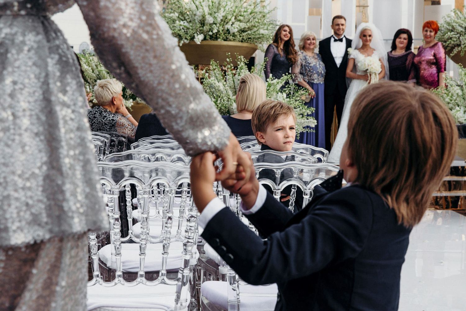 Wedding guests raise champagne glasses in a celebratory toast during an elegant outdoor reception.
