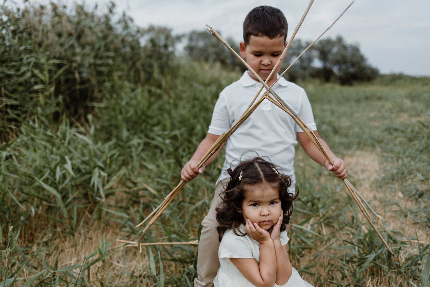 Children playing outdoors with sticks and natural elements in a candid lifestyle photo series.