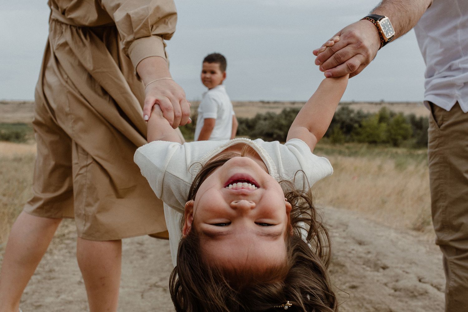 A joyful couple embraces and laughs together during a sunset photoshoot in a desert landscape.