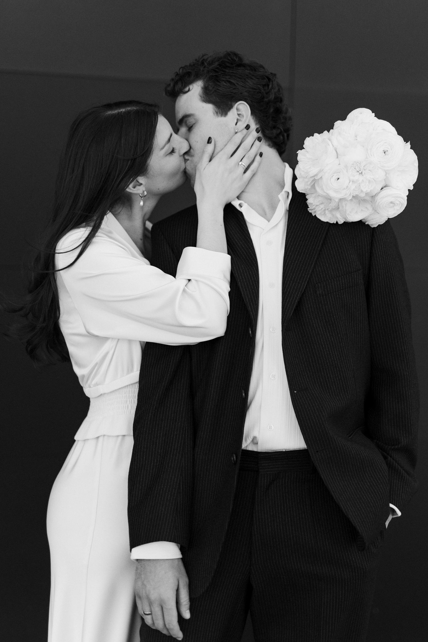 Black and white photo series showing a couple in white and black formal attire in romantic poses against dark backdrop.