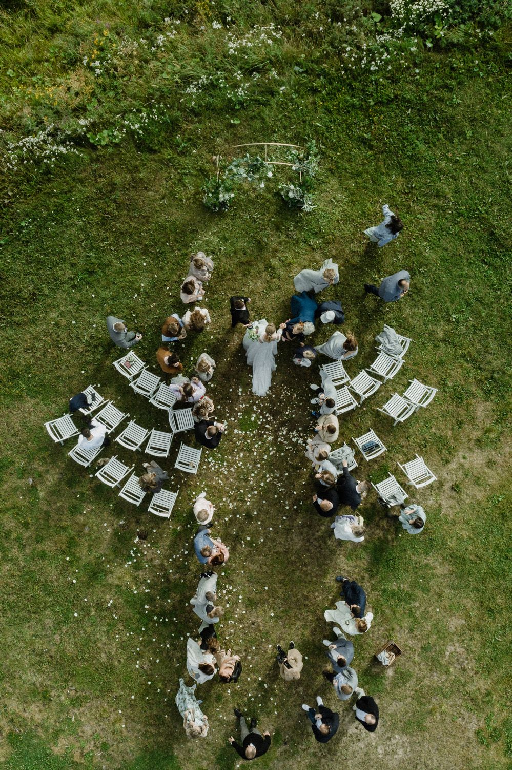 Bird's eye view of wedding guests arranged in unique seating pattern on grass.
