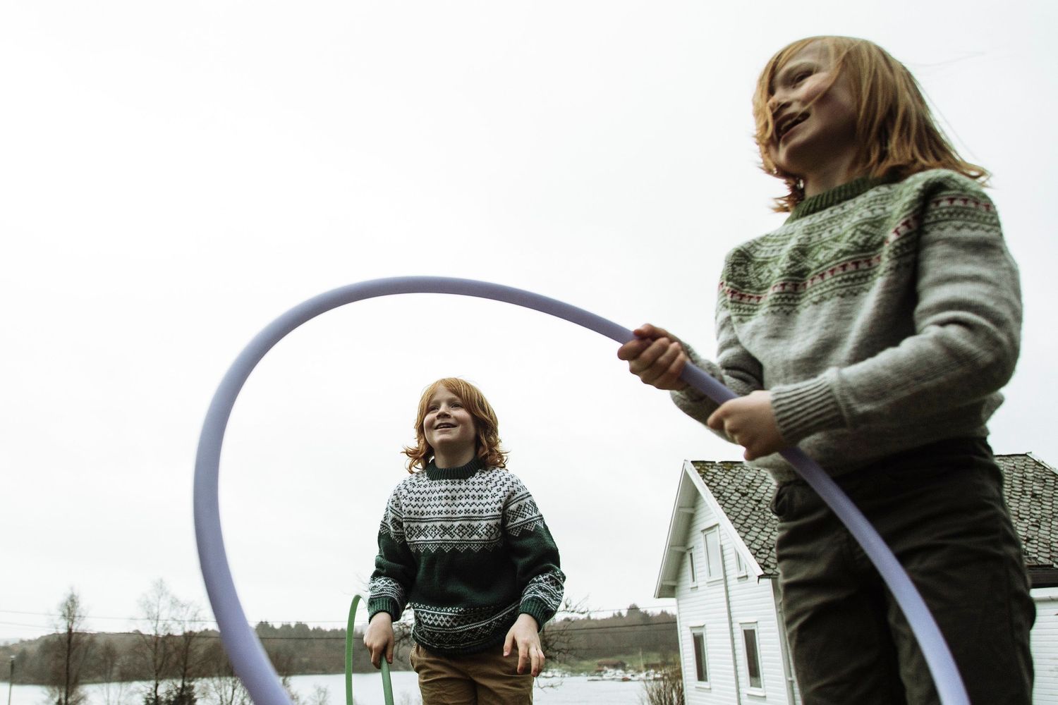 Two people playing with blue hoop ribbons outdoors in winter.