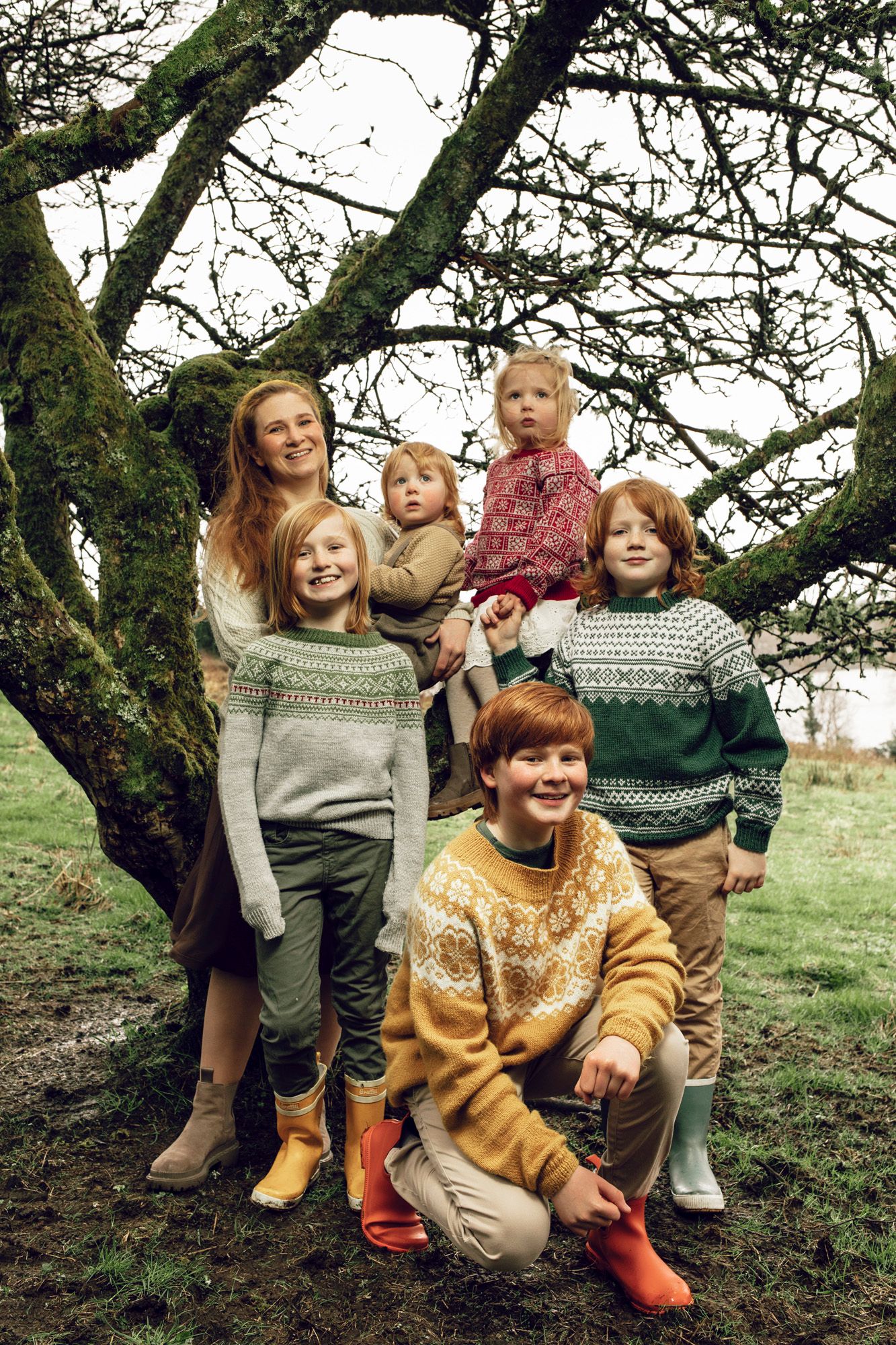 Joyful gathering under a tree branch with everyone wearing cozy winter sweaters.