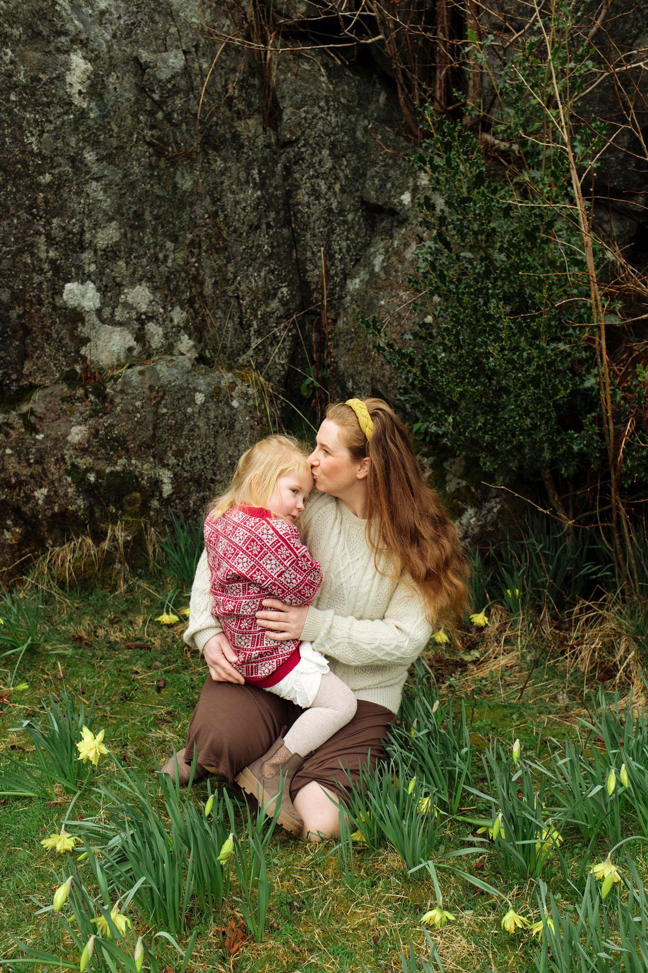 Mother and child bonding together among blooming spring daffodils in a garden setting.