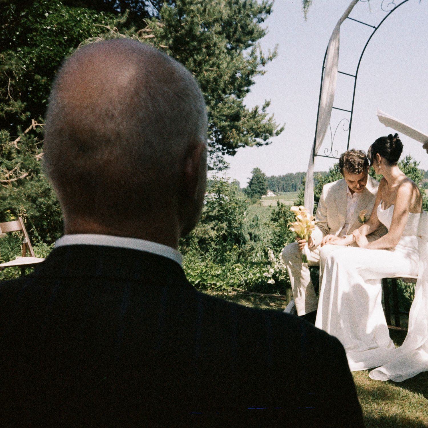A series of wedding ceremony photos showing the back of attendees and a white dress against an outdoor garden setting.
