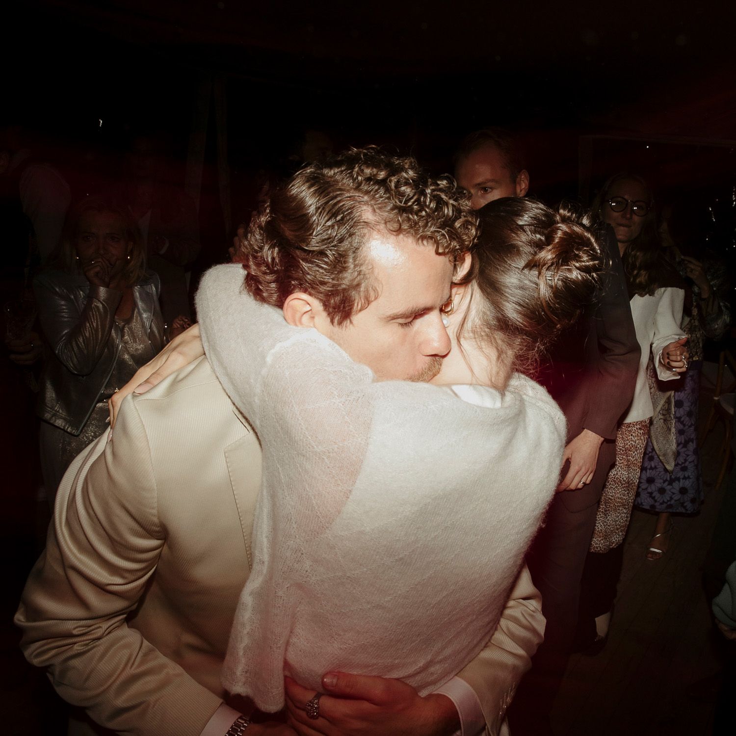 People dancing together in a dimly lit room during what appears to be a celebration or party event.