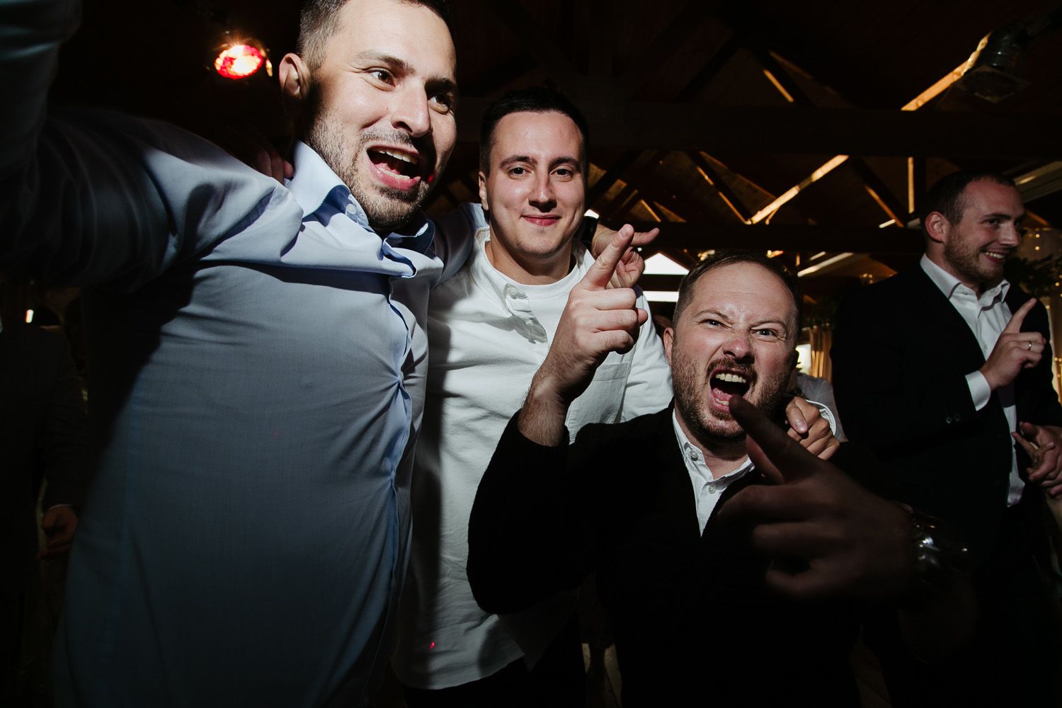 Group of celebrants laughing and enjoying themselves during a dimly lit reception.