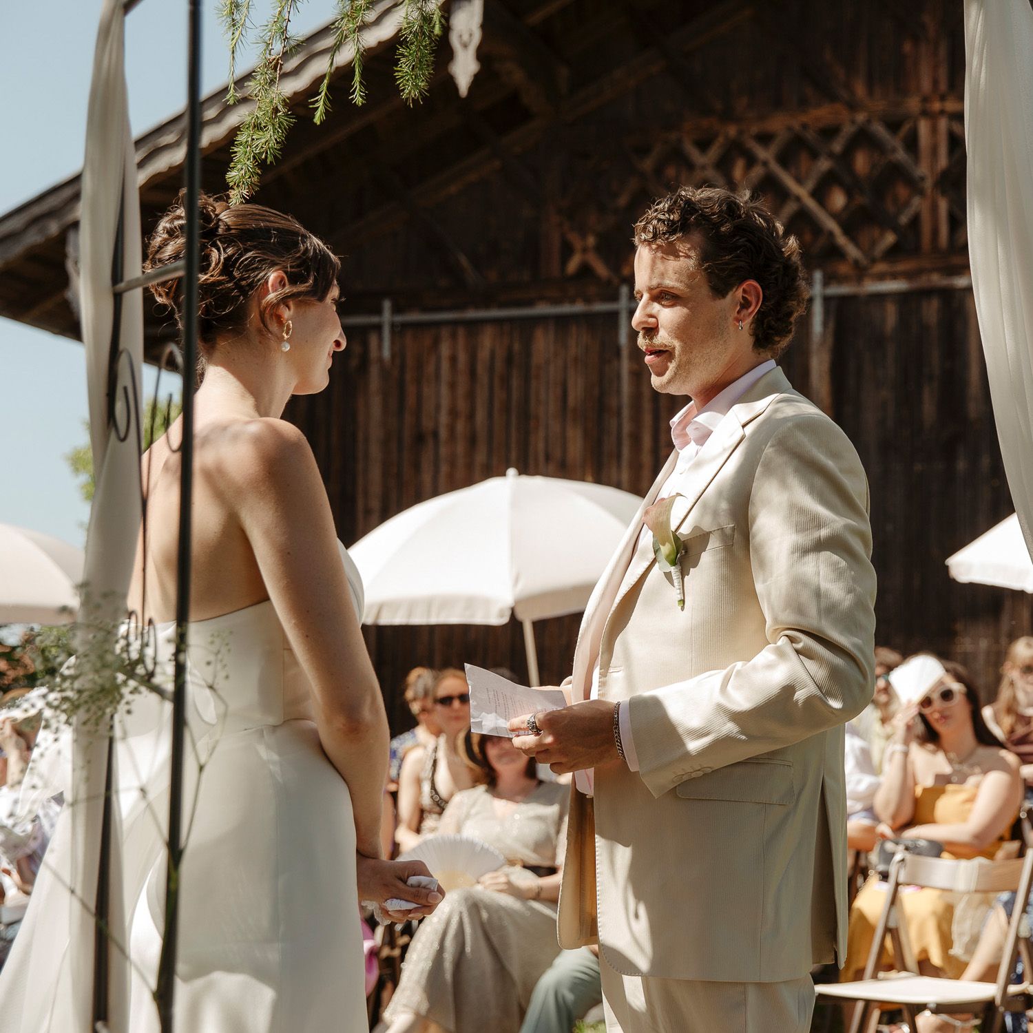 A couple exchanges vows during an intimate ceremony in a rustic barn setting with natural light streaming in.