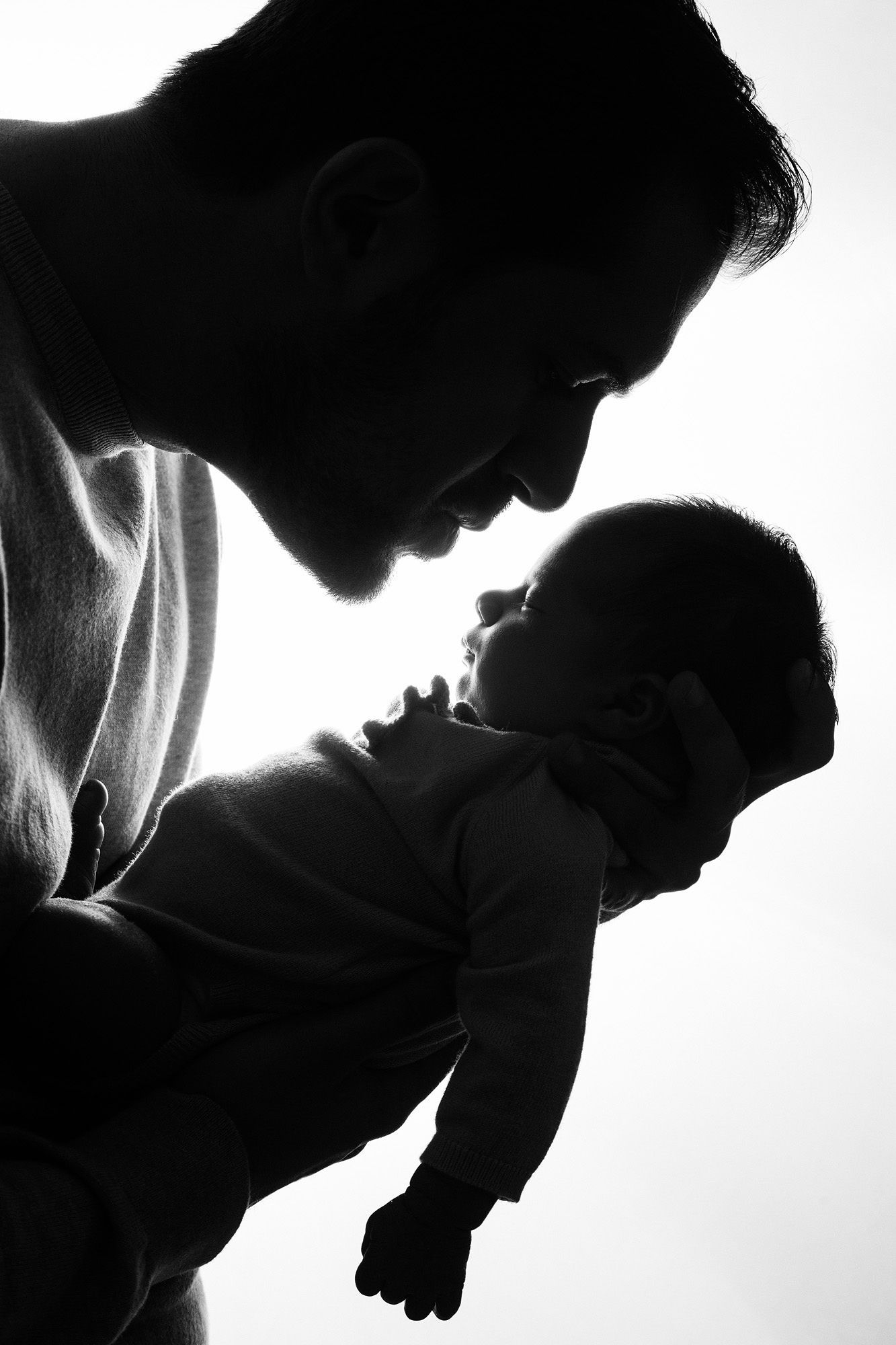 Dramatic black and white silhouettes show intimate parent and child moments in artistic profile.