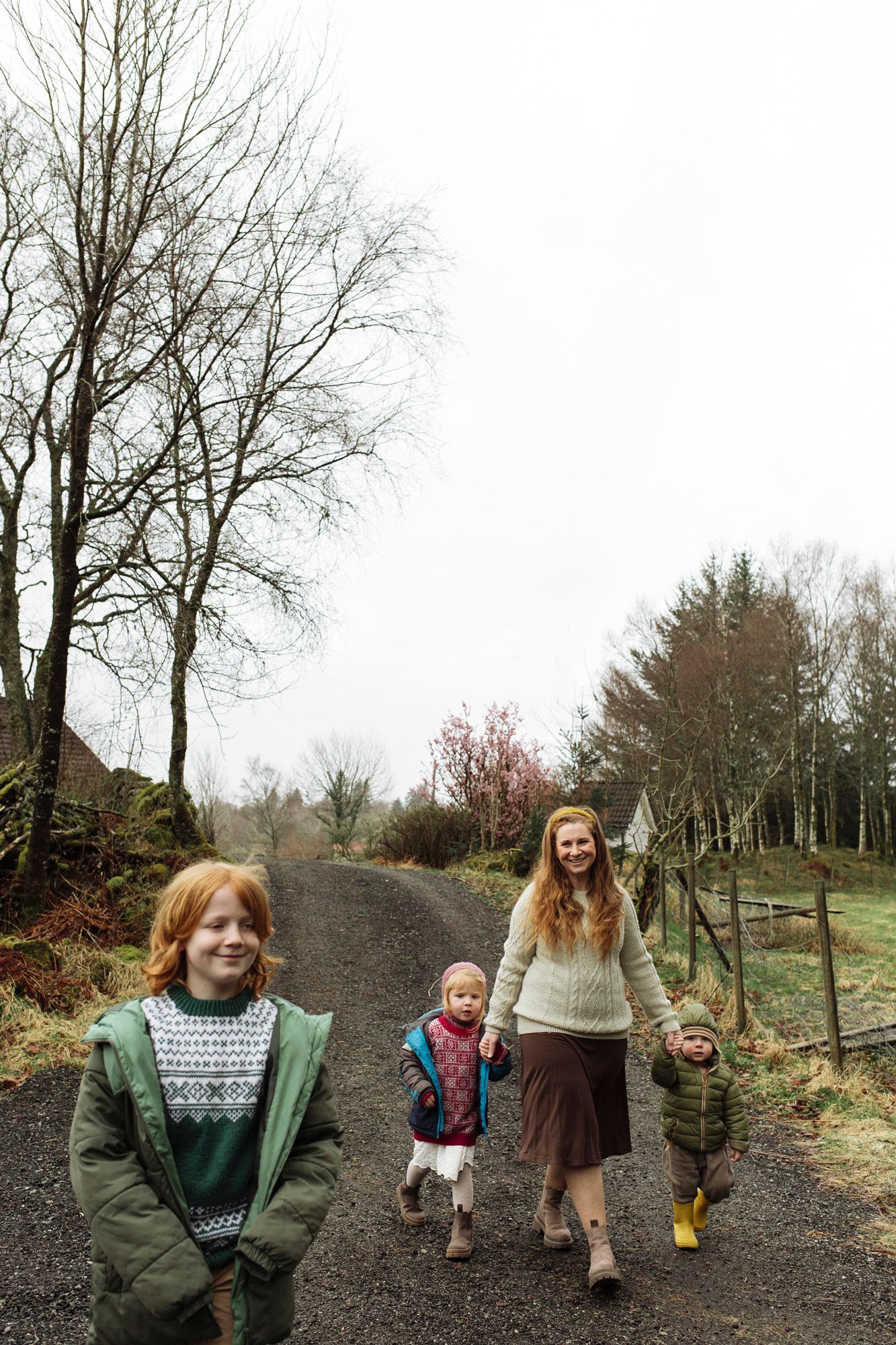 Family group walking together on a wooded path during autumn or winter.