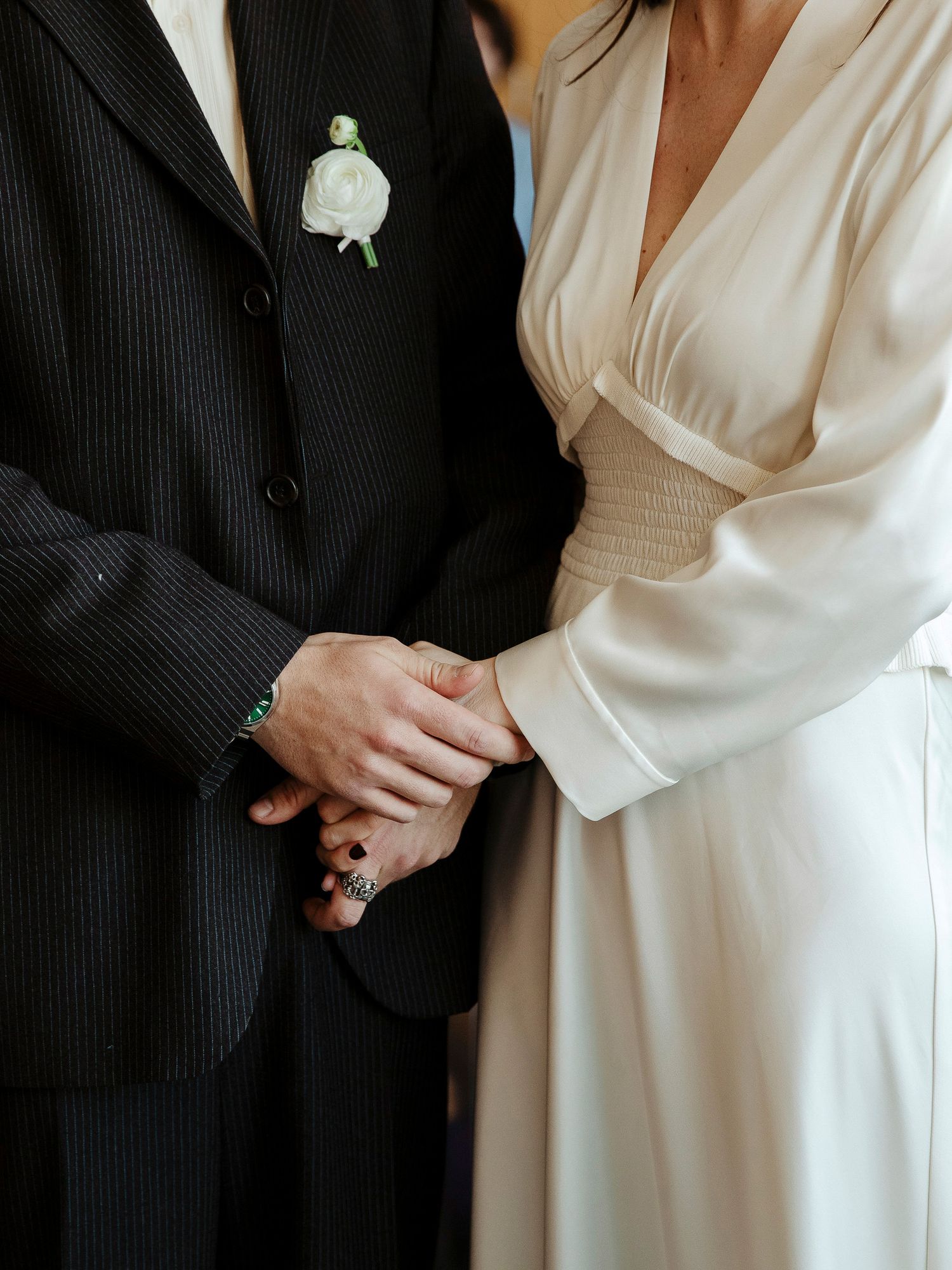 A series of elegant black and white wedding photos showing close-up details of formal attire and clasped hands.