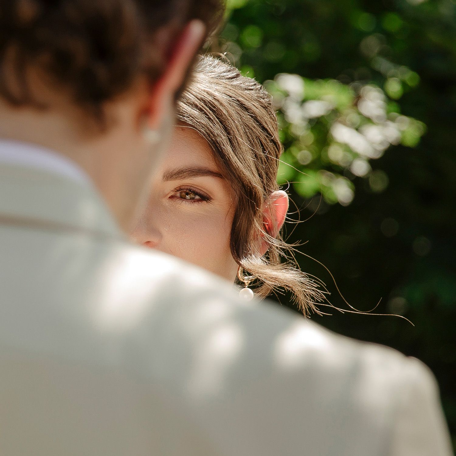 Close-up portrait of a person with soft lighting and blurred greenery in the background.