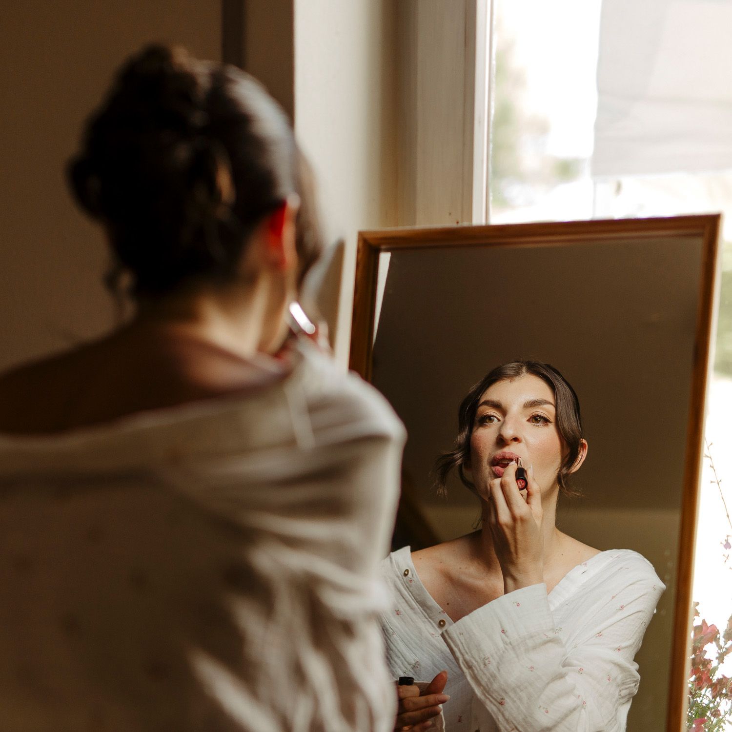A bride in white dress poses for a series of artistic portraits in natural window light.
