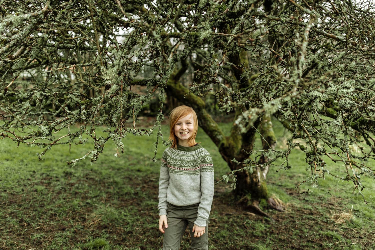 Group of people in warm sweaters having fun in a green outdoor setting.